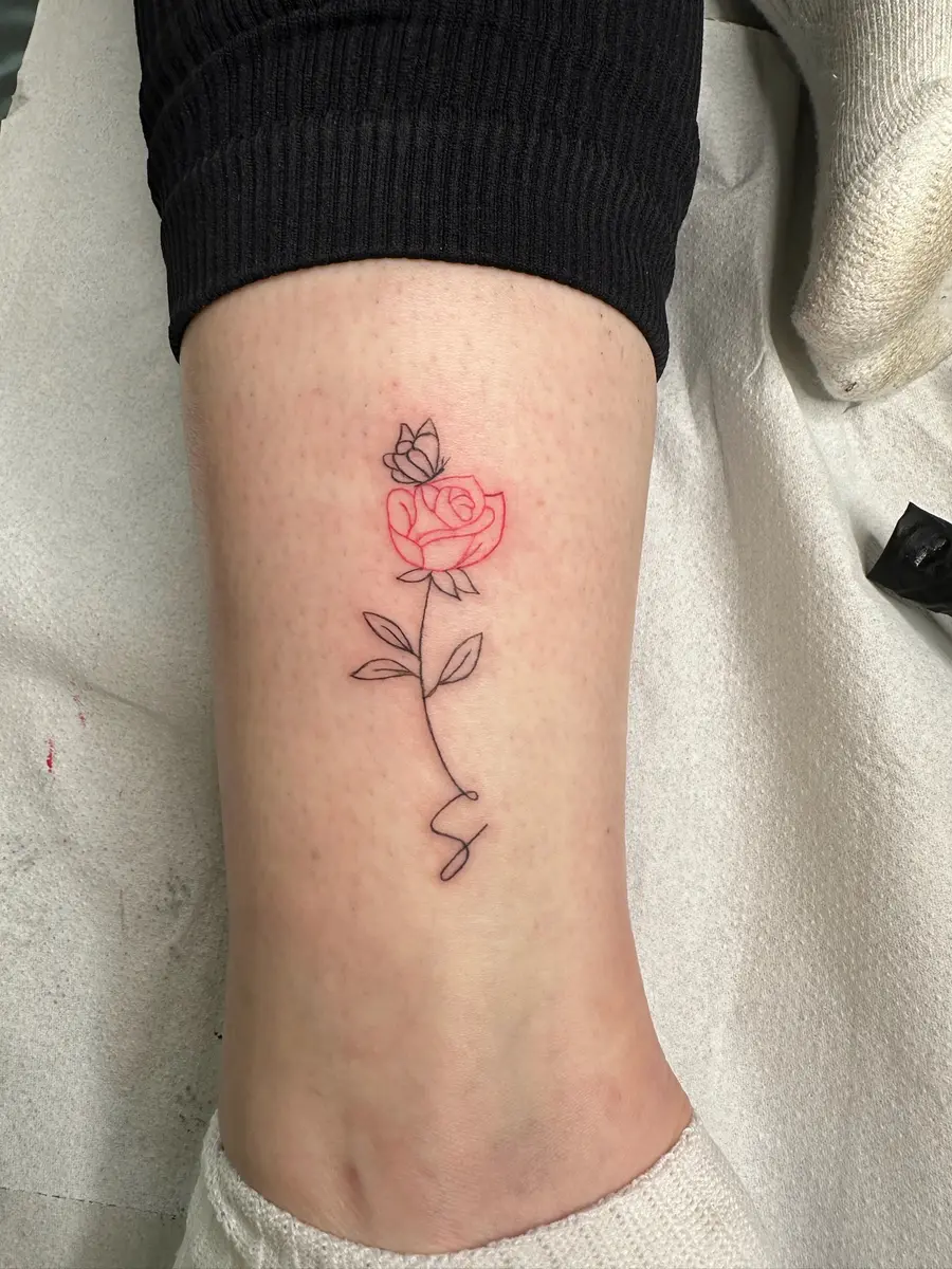 Fine line rose tattoo with a touch of colour on a forearm by Sophie, Devon studio serving Exeter clients